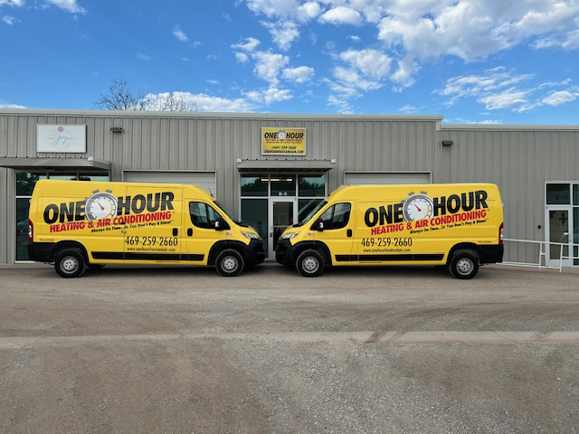 Two yellow vans for _One Hour Heating & Air Conditioning,_ parked outside a modern building, showcasing the business's branding oh_bfp_ohio-2-handwithphoneedit